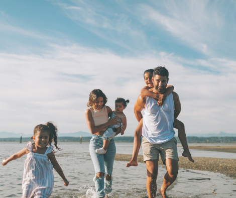 Family with young children walking along the water. Canada Psychotherapy provides a safe and supportive space to explore connections within your family.